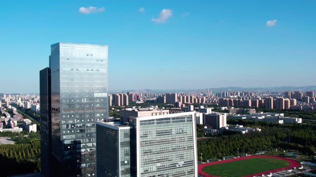 An aerial shot of a modern urban area featuring high-rise buildings, green spaces and a clear blue sky.