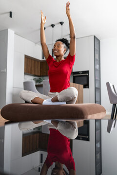 Woman practicing meditation in modern home setting with reflection on surface