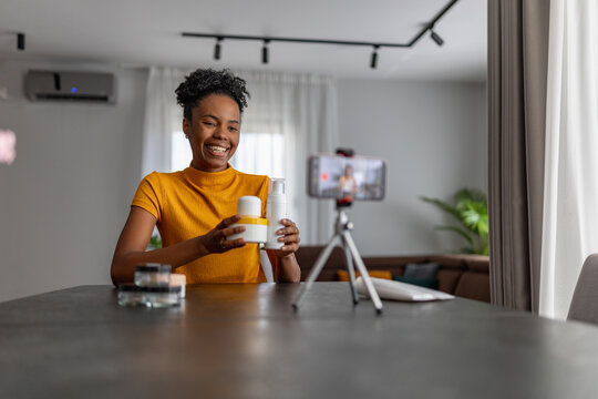 Woman demonstrates skincare products while recording video at home