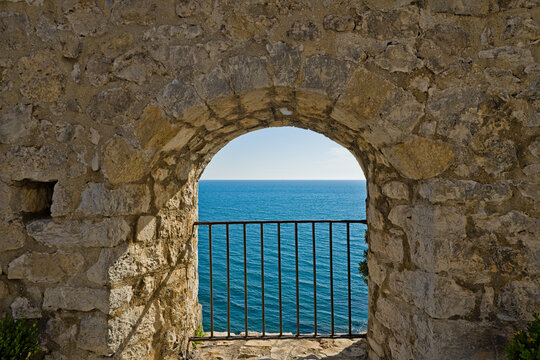 Ancient stone archway with blue metal gate overlooking Adriatic Sea in Ulcinj