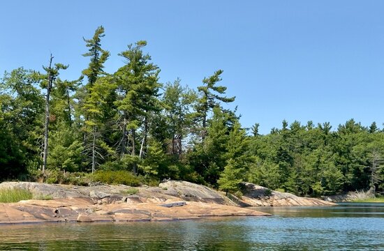 Weathered pink Granite, windswept pines and calm waters in the Massasauga Provincial Park near Parry Sound Ontario Canada