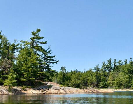 Weathered pink Granite, windswept pines and calm waters in the Massasauga Provincial Park near Parry Sound Ontario Canada