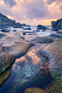 Scene featuring rocks on beach of fjord of Norwegian sea in winteron sunset. Utakliev beach, Lofoten islands, Norway