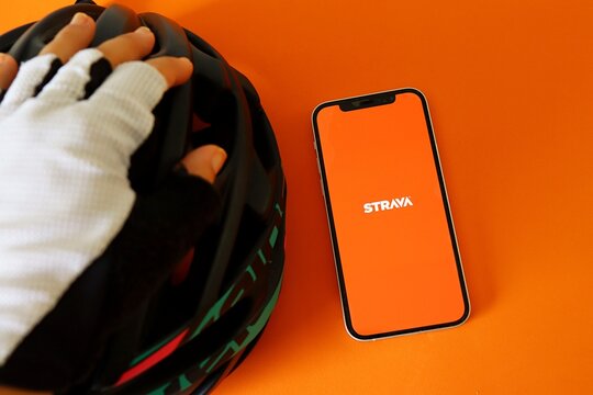 Salvador, Brazil - August 16, 2026: Cyclist using Strava app on smartphone screen. Cycling concept. Strava is a popular fitness tracking app for runners, cyclists, and other athletes. 