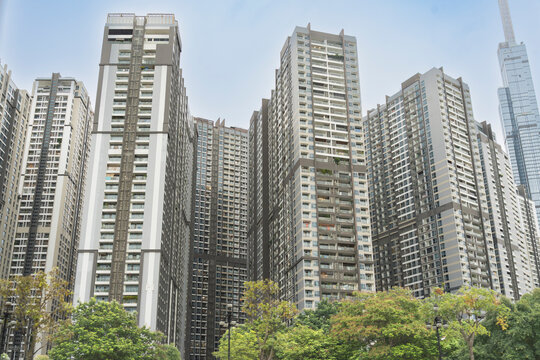 Modern high-rise residential apartment towers towering over green trees, with Landmark 81 visible in the background in Ho Chi Minh City, Vietnam.