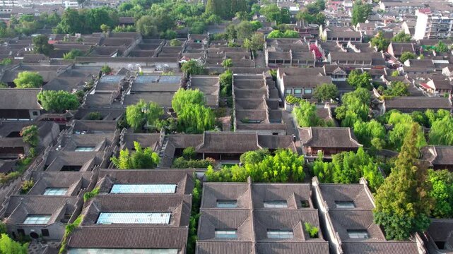 Aerial shot of a dense cluster of traditional ancient courtyard buildings with surrounding green trees, forming a historic architectural complex.