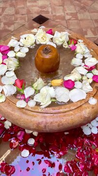 traditional brass fountain with clear bubbling water decorated with fresh red rose and white petals floating in basin inside luxury riad courtyard in Marrakech Morocco