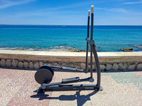 Outdoor workout machine at seaside promenade in Calpe, Spain with clear ocean water in the background
