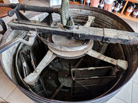 Top view of an antique mechanical honey extractor machine with internal metal frames in a beekeeping workshop