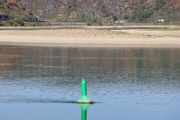 Navigation buoy marking the Rhine channel beside a large exposed gravel bank © Philipp