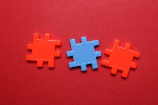 Children's plastic construction set, puzzles on red background. Teamwork, business concept
