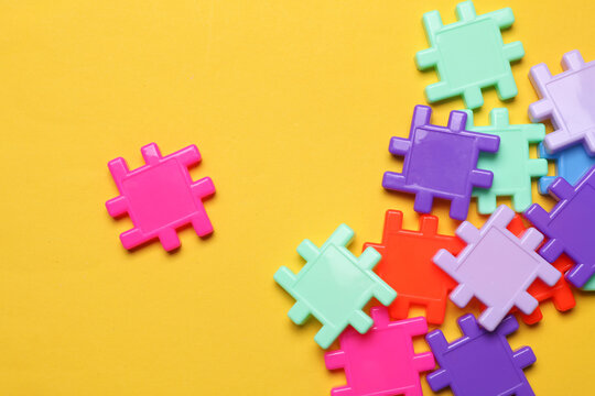 Children's plastic construction set, puzzles on yellow background. Teamwork, business concept