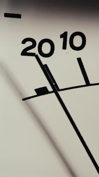 Analog VU meter needle pointing past twenty decibels on white display scale. Extreme close-up vertical shot