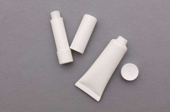 Mockup of white lipstick and cream tubes on gray background