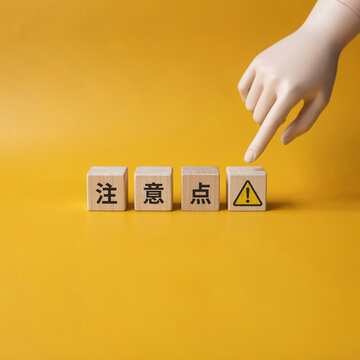 Mannequin hand points directly toward wooden toy blocks featuring Japanese warning characters on yellow.