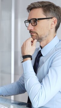 Thoughtful businessman working at his desk, intently looking at a computer screen while contemplating business solutions and actively developing new corporate strategies