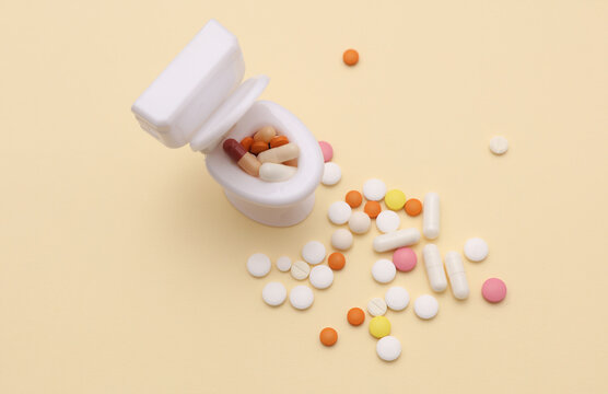Miniature toy toilet and many pills on beige background