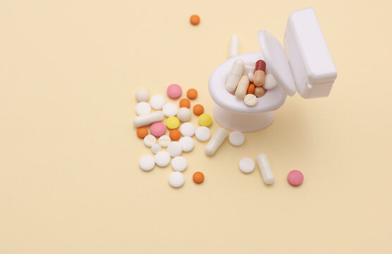 Miniature toy toilet and many pills on beige background