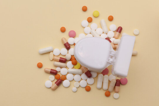 Miniature toy toilet and many pills on beige background