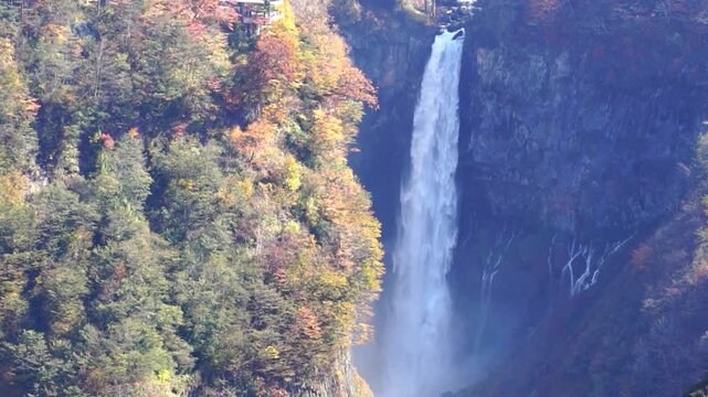 Kegon falls is a majestic waterfall cascading down through lush autumn foliage and rock faces with small stream in stunning natural landscape in Japan.