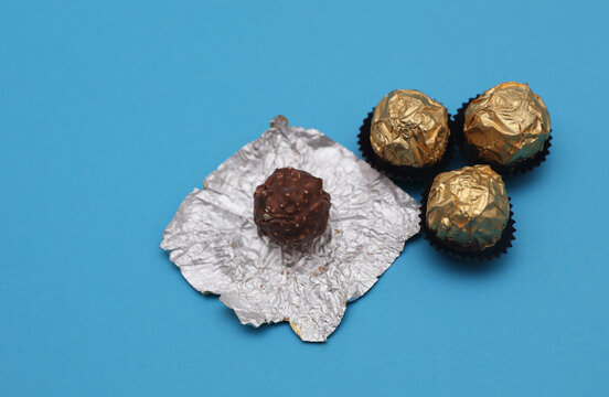 Chocolate candy balls wrapped in gold foil on blue background