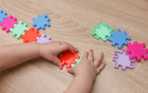 Baby hand plays with Plastic construction puzzle on a table. Games for developing toddlers logic and motor skills