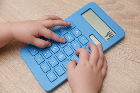 Financial literacy. Baby hands holding calculator.