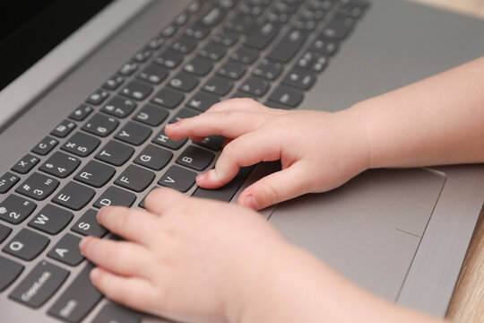 Baby hands typing on a laptop keyboard