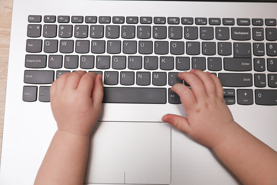 Baby hands typing on a laptop keyboard