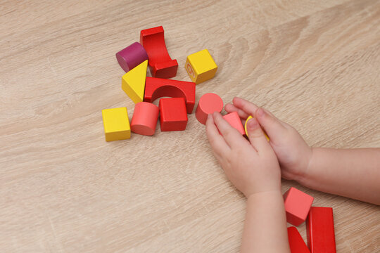 Baby Hands playing with wooden colored cubes on a table. Motor skills development.