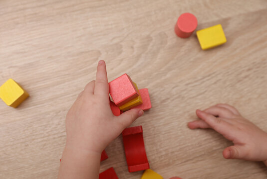Baby Hands playing with wooden colored cubes on a table. Motor skills development.
