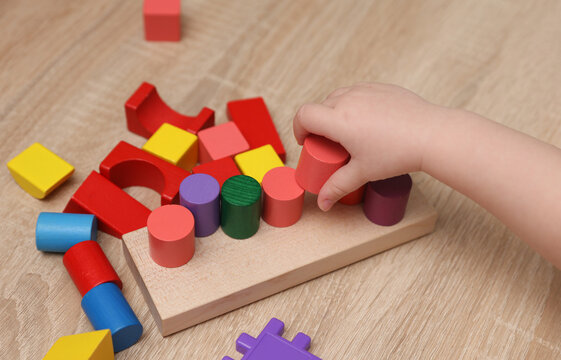 Toddler plays with a wooden color sorter. Develop toddler's logic and motor skills.