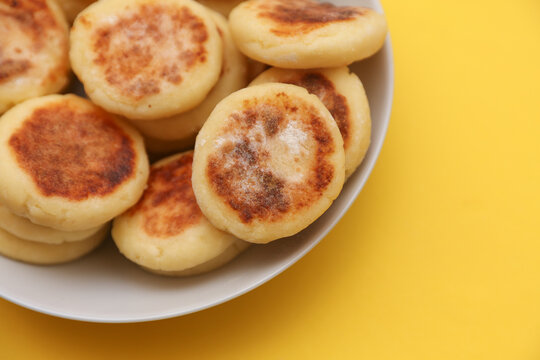 Homemade delicious syrniki, cheese pancakes in a plate on yellow background