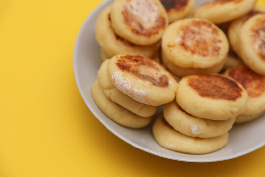 Homemade delicious syrniki, cheese pancakes in a plate on yellow background