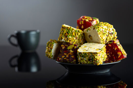 Turkish delights and black coffee on a black reflective background.