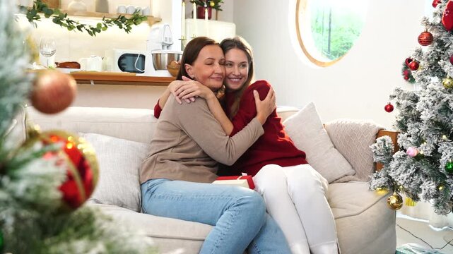 The daughter hugged her mother, gave her a gift, and they sat together on the sofa to celebrate the Christmas and New Year holidays.