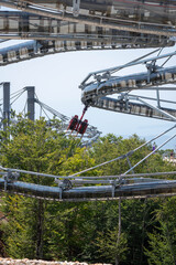 Fototapeta premium Tourist Riding a Suspended Mountain Adventure Ride Above Bay of Kotor, Montenegro, Scenic Summer Travel and Thrill Attraction