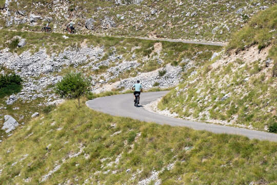 Cyclists Riding on Winding Mountain Road in Montenegro, Scenic Outdoor Cycling Adventure Through Rocky Highland Landscape