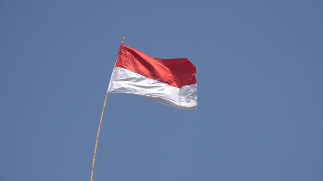 Indonesian red and white national flag waving proudly against a clear blue sky, perfectly capturing the vibrant spirit and patriotic pride for Indonesia's 81st Independence Day anniversary celebration