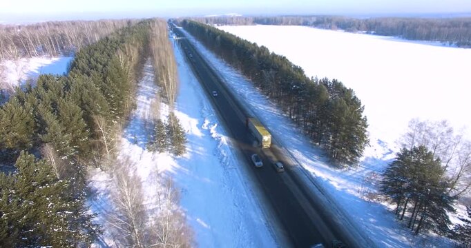 An aerial view of a snow-covered road flanked by trees in Kemerovo  showcasing a serene winter landscape.