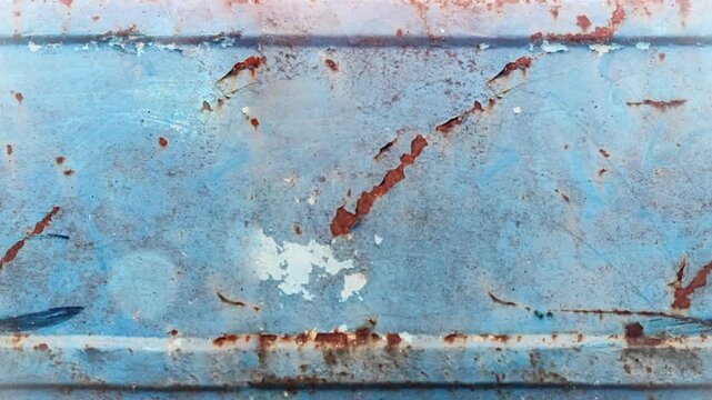 Seamless 4K looping vertical movement across a weathered blue painted metal surface with scratches and rust marks. Ideal for industrial backgrounds and creative projects.