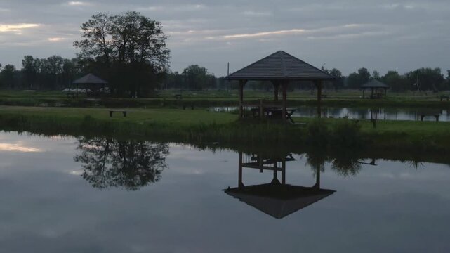 Wooden gazebo reflected in the calm water of a lake