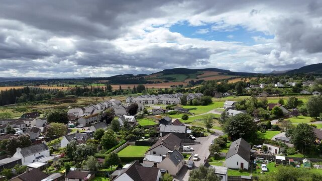 Dramatic landscape video of Evanton village featuring cloudy sky over residential homes, farmland, and Cromarty Firth bay, Scottish Highlands, UK