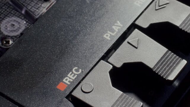 Finger pushing down play button on retro cassette tape player deck to turn on music. Detailed macro shot