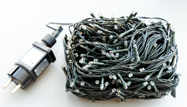 Bundle of tangled LED string lights with power adapter on white