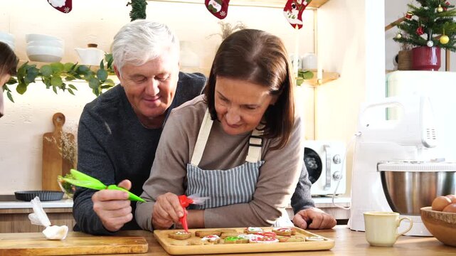 Grandpa and Grandma's family happily decorated gingerbread cookies together with cream cheese, preparing food for a Thanksgiving and Christmas party at home. 