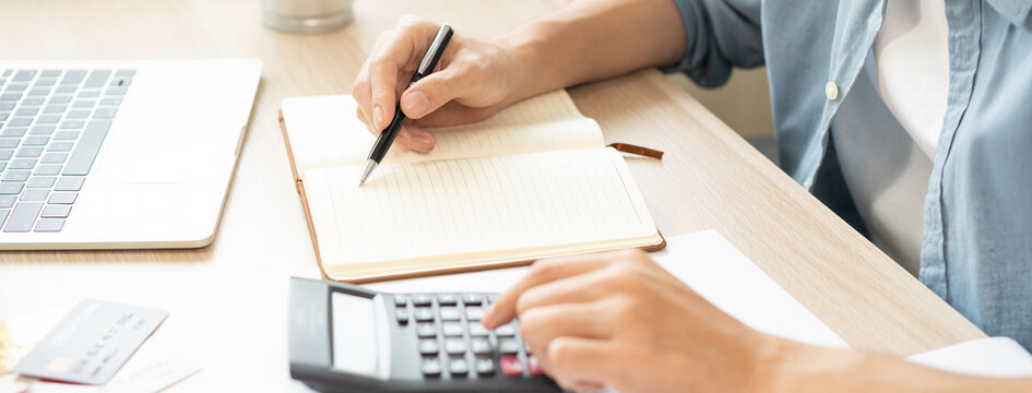 Saving money wealth concept, asian young business man, male using calculator for calculate saving cost, cash finance planning to spend enough money on his income for save money, payment tax, investing