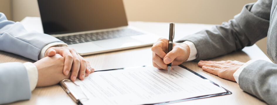 Close up of business people hands signing contract agreement document on clipboard at desk in office, lawyer or businessman putting signature filling corporate legal paperwork form.