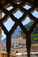  Pionowy kadr przedstawiający malowniczy widok na miasteczko Amalfi na Wybrzeżu Amalfi, region Kampania, Włochy, sfotografowany przez zabytkowe, łuki  krużganków Katedry Św. Andrzeja © Grzegorz