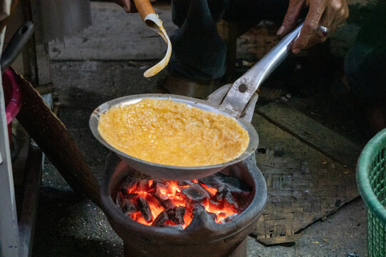 Kerak telor is a traditional Betawi street food from Jakarta, Indonesia, cooked over a small clay stove using glowing charcoal embers.